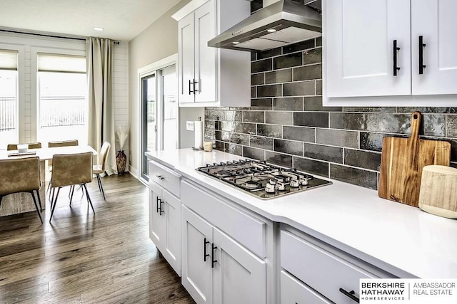 kitchen featuring white cabinetry, tasteful backsplash, dark hardwood / wood-style floors, stainless steel gas stovetop, and wall chimney range hood