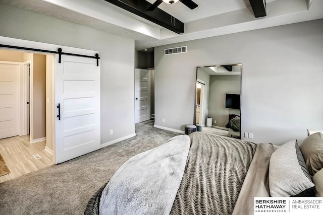 carpeted bedroom featuring beam ceiling and a barn door