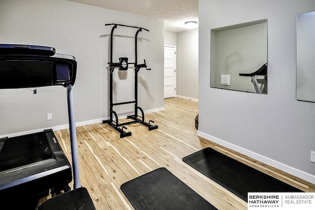 workout area with baseboards and wood finished floors