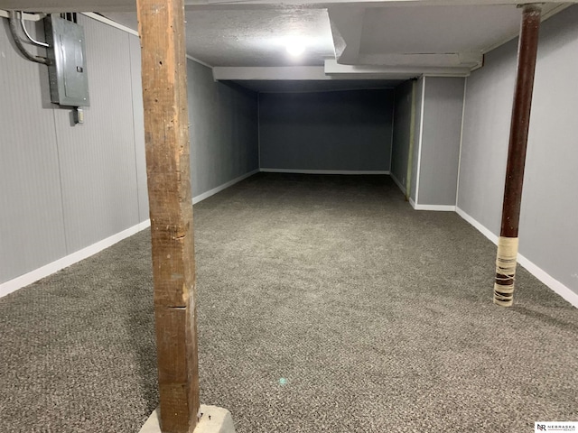 basement with electric panel, a textured ceiling, and dark colored carpet