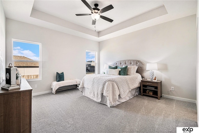 carpeted bedroom featuring ceiling fan and a tray ceiling