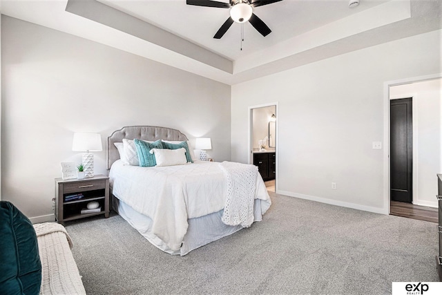 carpeted bedroom featuring ceiling fan, connected bathroom, and a raised ceiling