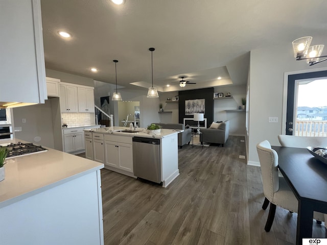 kitchen with appliances with stainless steel finishes, an island with sink, sink, white cabinets, and hanging light fixtures