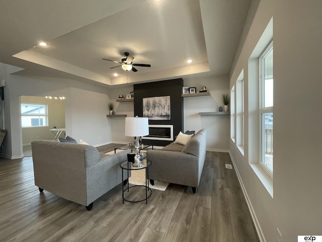 living room featuring hardwood / wood-style flooring, ceiling fan, and a raised ceiling