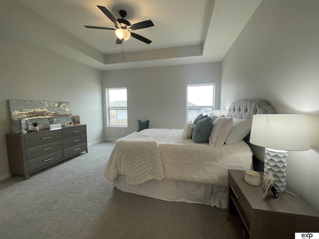 carpeted bedroom with a tray ceiling and ceiling fan