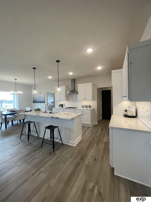 kitchen featuring white cabinetry, wall chimney exhaust hood, dark hardwood / wood-style flooring, and pendant lighting