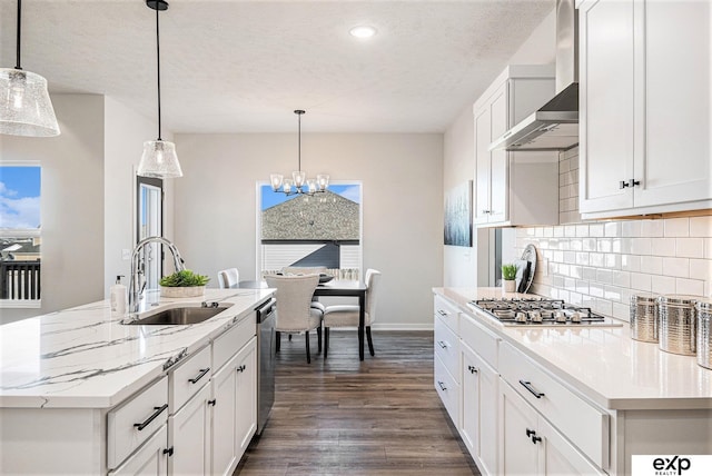 kitchen featuring stainless steel appliances, an island with sink, sink, and wall chimney range hood