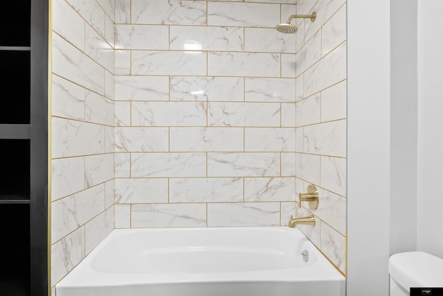 bathroom featuring tiled shower / bath combo and toilet