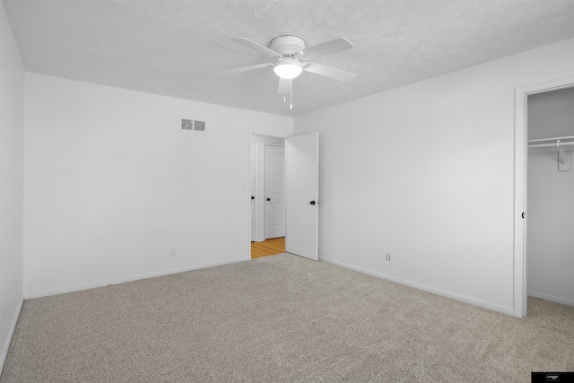 unfurnished bedroom with ceiling fan, light carpet, a textured ceiling, and a closet