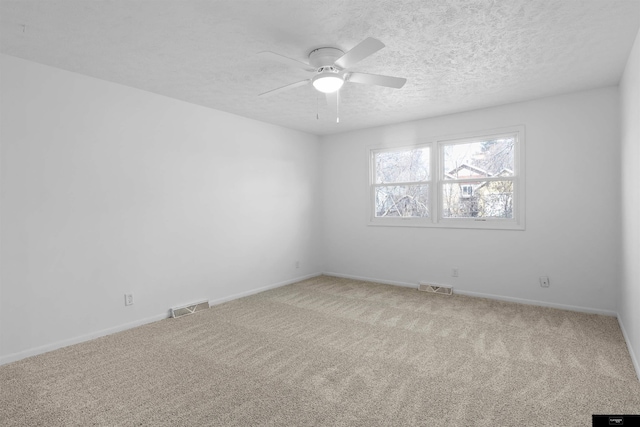 carpeted empty room featuring ceiling fan and a textured ceiling