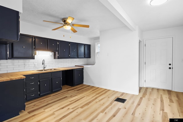 kitchen with sink, butcher block countertops, tasteful backsplash, light wood-type flooring, and ceiling fan