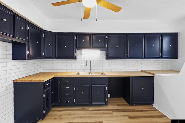 kitchen with sink, light hardwood / wood-style flooring, wood counters, and decorative backsplash