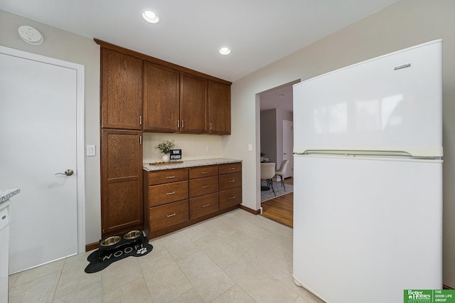 kitchen featuring light stone countertops and white fridge