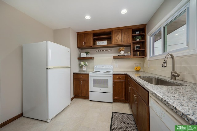 kitchen with light stone counters, sink, white appliances, and backsplash