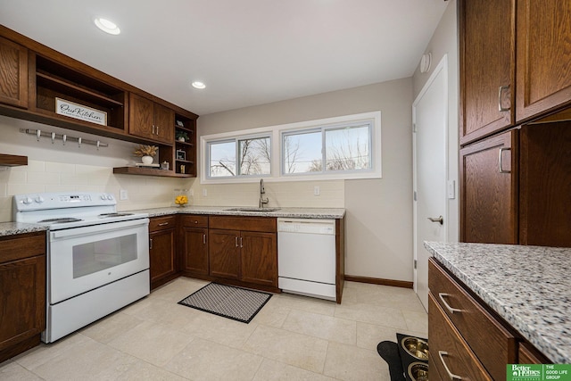 kitchen featuring sink, light stone counters, white appliances, and decorative backsplash