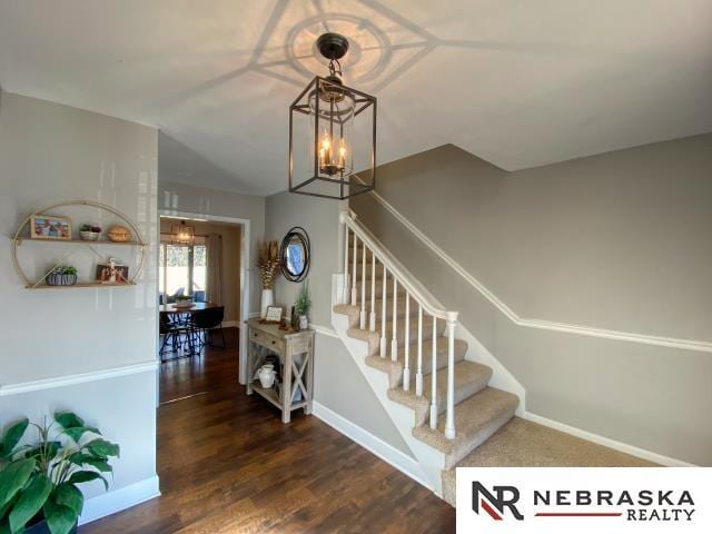 stairway with an inviting chandelier and wood-type flooring