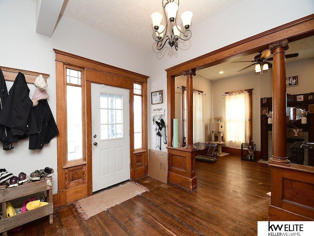 entrance foyer featuring an inviting chandelier, dark hardwood / wood-style flooring, decorative columns, and a textured ceiling