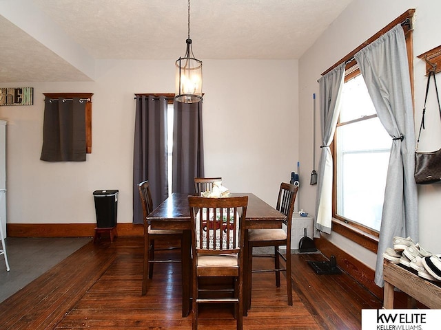 dining space featuring a chandelier, dark hardwood / wood-style floors, and a textured ceiling