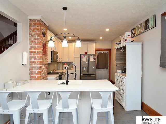 kitchen with sink, a breakfast bar area, tasteful backsplash, stainless steel fridge with ice dispenser, and kitchen peninsula