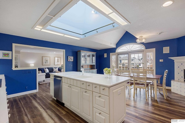 kitchen featuring dark wood-type flooring, sink, dishwasher, and an island with sink