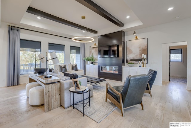 living room with light hardwood / wood-style flooring, a fireplace, and beamed ceiling