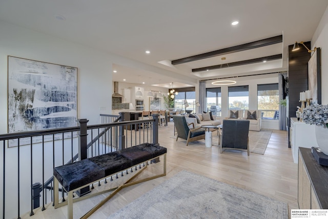 living room with beamed ceiling, a notable chandelier, and light wood-type flooring