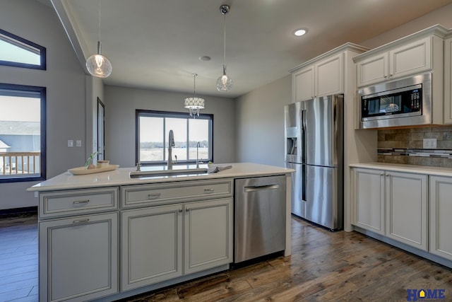 kitchen with a sink, light countertops, appliances with stainless steel finishes, backsplash, and dark wood-style floors