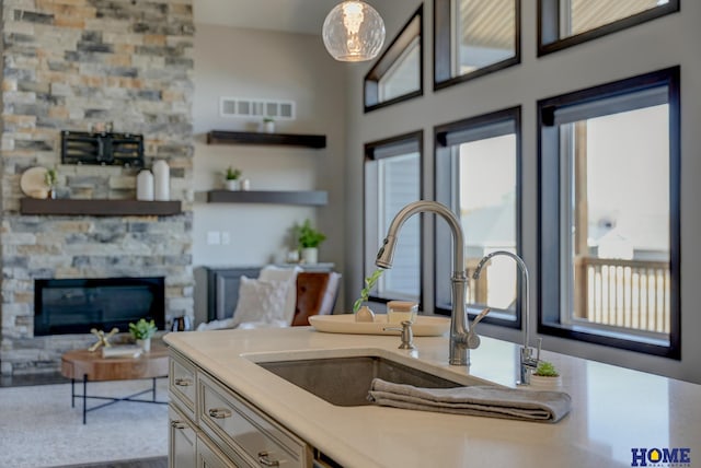 kitchen featuring a fireplace, light countertops, visible vents, open floor plan, and a sink