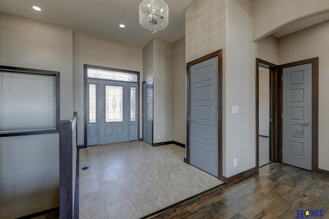 entryway with baseboards, recessed lighting, wood finished floors, and a notable chandelier