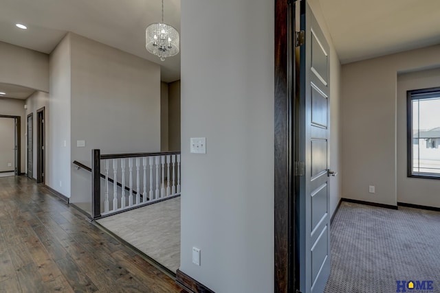 corridor featuring baseboards, wood finished floors, an upstairs landing, a notable chandelier, and recessed lighting