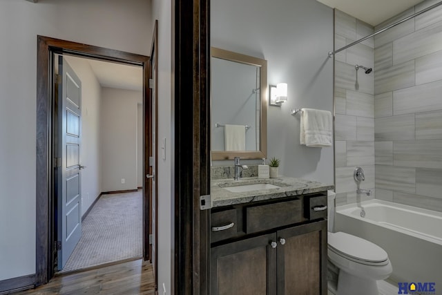 full bath with toilet,  shower combination, wood finished floors, and vanity