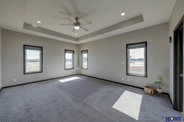 empty room featuring carpet floors, recessed lighting, a raised ceiling, a ceiling fan, and baseboards