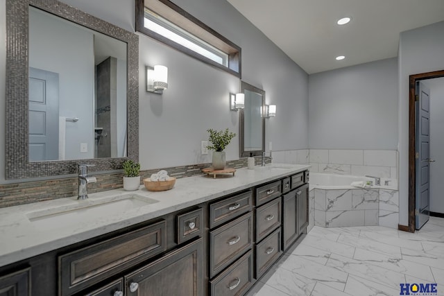 bathroom with a garden tub, marble finish floor, double vanity, and a sink