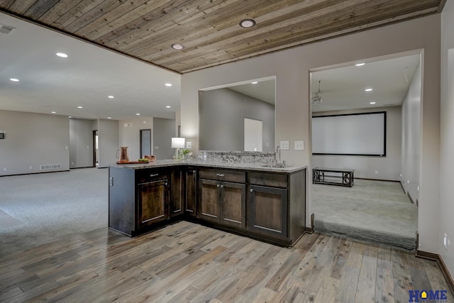 kitchen featuring visible vents, open floor plan, dark brown cabinetry, light stone countertops, and wooden ceiling