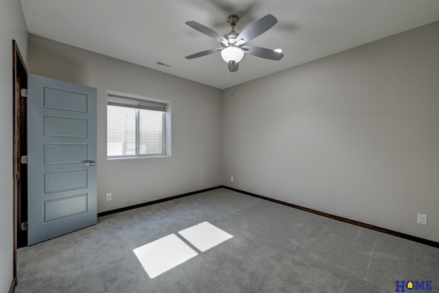 carpeted spare room with visible vents, ceiling fan, and baseboards