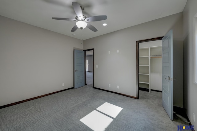 unfurnished bedroom featuring baseboards, a closet, a walk in closet, and light colored carpet