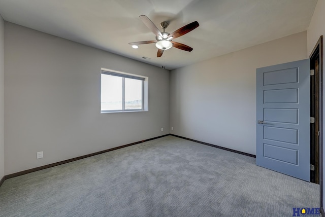 spare room with light carpet, ceiling fan, visible vents, and baseboards