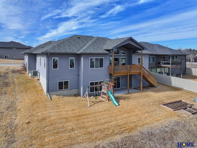 rear view of house with a shingled roof, a lawn, stairway, a patio area, and fence