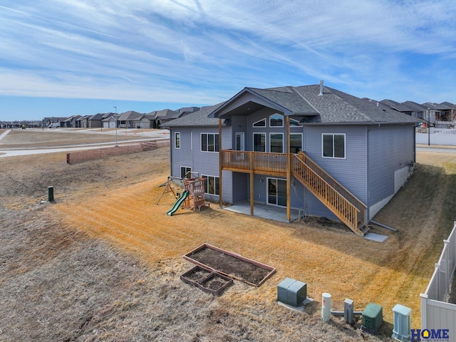 back of house featuring a patio, a lawn, fence, a wooden deck, and stairs