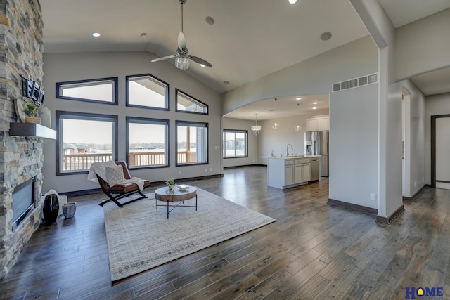 living room with dark wood-style flooring, visible vents, and a stone fireplace