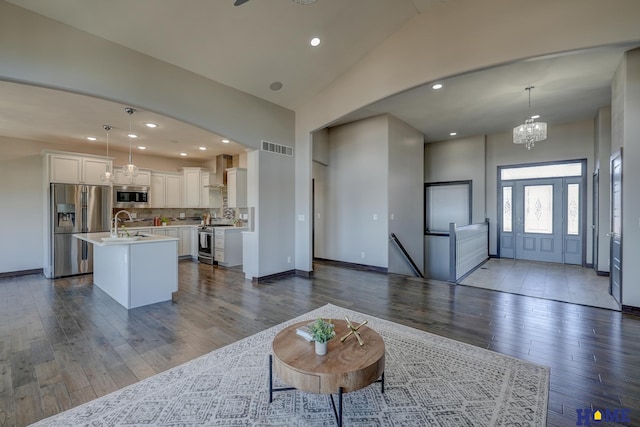 living area featuring lofted ceiling, recessed lighting, visible vents, dark wood-style floors, and an inviting chandelier