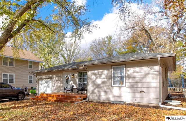 view of front of house featuring a garage, a trampoline, and a deck