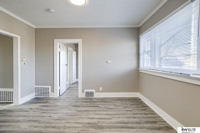 empty room with ornamental molding and light hardwood / wood-style floors