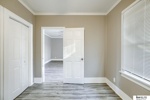 unfurnished bedroom with crown molding, a closet, and light hardwood / wood-style flooring