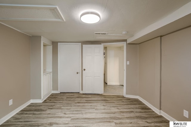 basement featuring a textured ceiling and light wood-type flooring