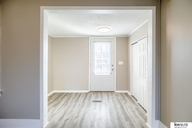 doorway to outside featuring ornamental molding, a textured ceiling, and light hardwood / wood-style flooring