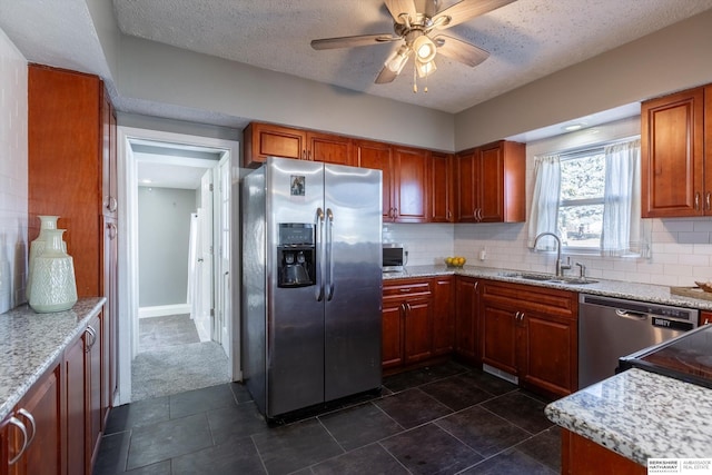 kitchen with sink, stainless steel appliances, light stone counters, tasteful backsplash, and dark carpet