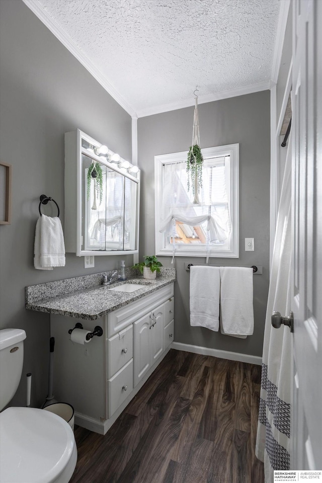 bathroom with toilet, crown molding, a textured ceiling, vanity, and hardwood / wood-style floors