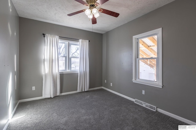 empty room featuring dark colored carpet, ceiling fan, and a textured ceiling