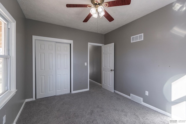 unfurnished bedroom with ceiling fan, a closet, carpet, and a textured ceiling